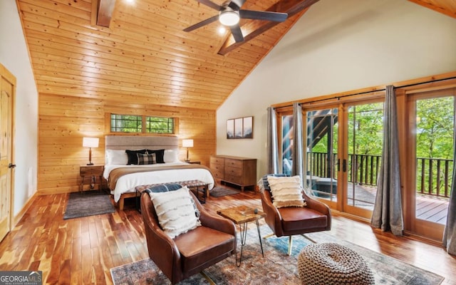 bedroom featuring multiple windows, high vaulted ceiling, access to outside, wood walls, and hardwood / wood-style floors