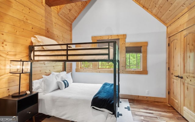 bedroom with lofted ceiling, wood ceiling, wood finished floors, and wooden walls