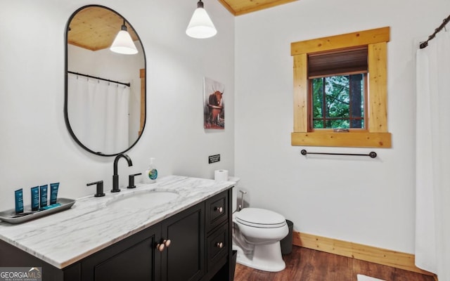 full bath featuring wood finished floors, toilet, vanity, and baseboards