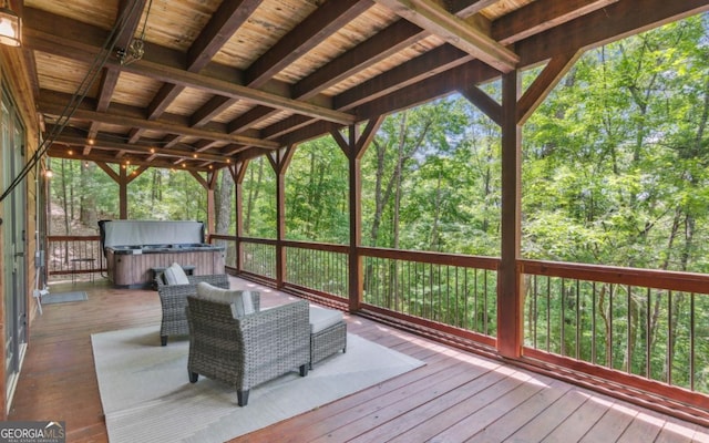 deck with a hot tub and a view of trees