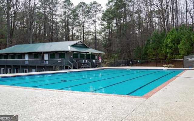 community pool featuring fence and view of scattered trees