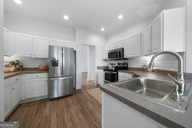 3047 Standing Rock Ct, Lithia Springs, GA 30122 - kitchen with dark wood-style flooring, a sink, appliances with stainless steel finishes, white cabinets, and ornamental molding