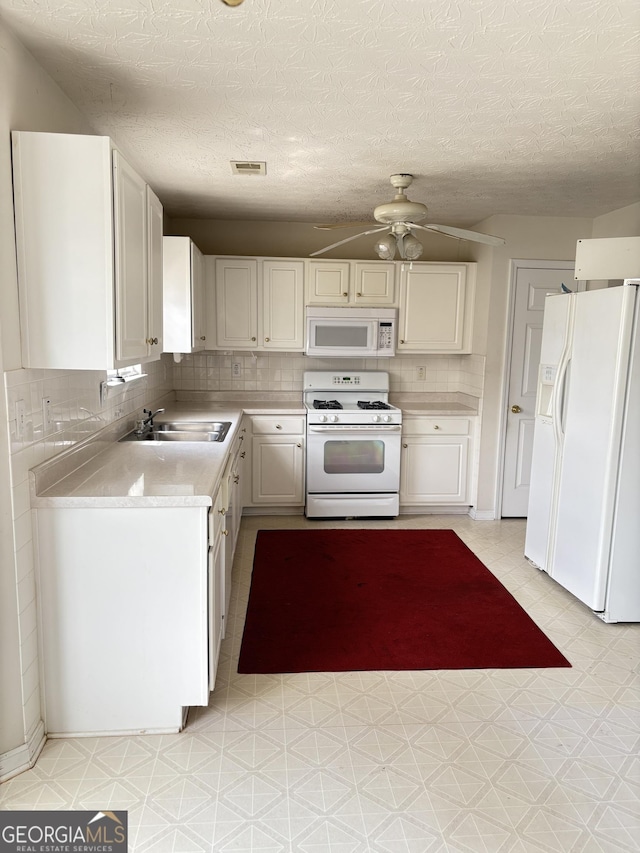 kitchen featuring visible vents, a ceiling fan, white appliances, light countertops, and a sink