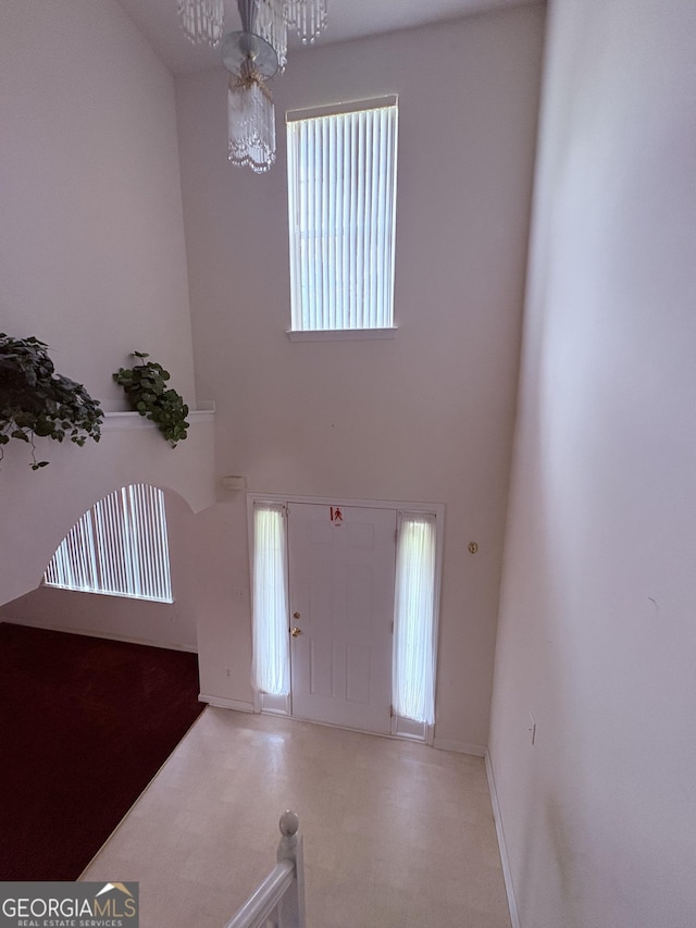entrance foyer featuring a high ceiling, a chandelier, and baseboards