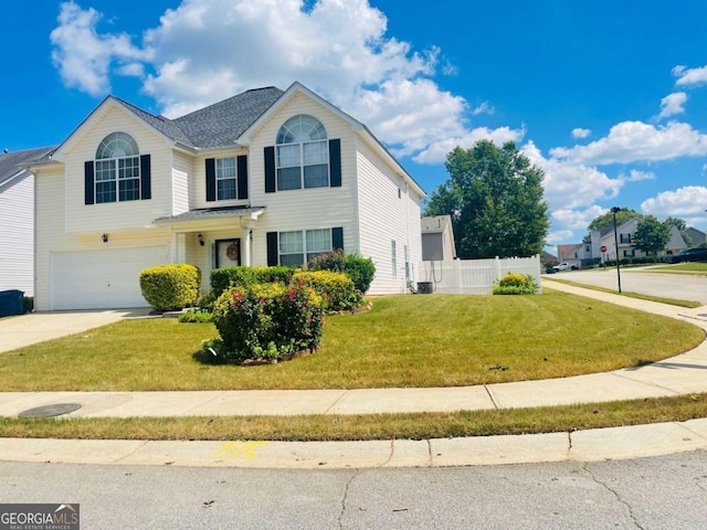 traditional home with fence, an attached garage, driveway, and a front yard