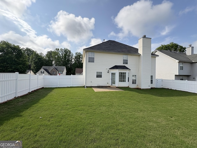 rear view of house featuring a lawn, a patio, a chimney, and a fenced backyard