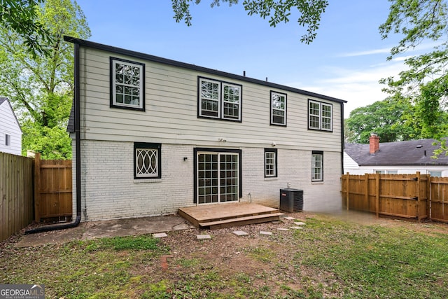 rear view of property featuring central air condition unit, a fenced backyard, and brick siding