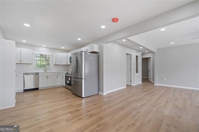 kitchen with light countertops, light wood-style floors, appliances with stainless steel finishes, and white cabinetry