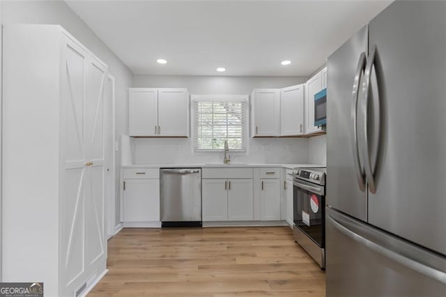 kitchen with light wood finished floors, stainless steel appliances, light countertops, and a sink