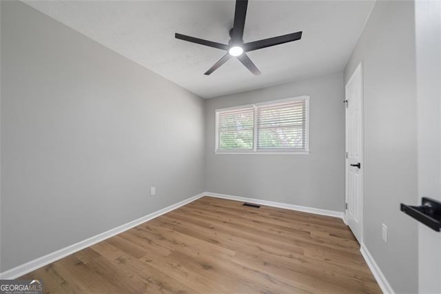 spare room featuring wood finished floors, baseboards, a ceiling fan, and visible vents