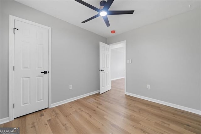 unfurnished bedroom with light wood-type flooring, baseboards, and ceiling fan