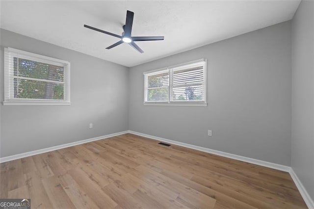 empty room featuring wood finished floors, visible vents, baseboards, and ceiling fan
