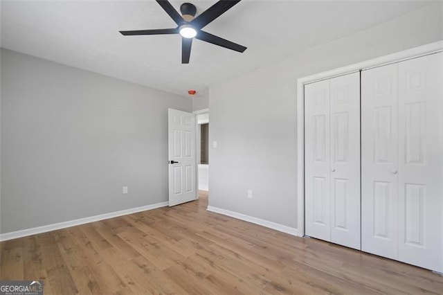 unfurnished bedroom with light wood-type flooring, a closet, baseboards, and ceiling fan