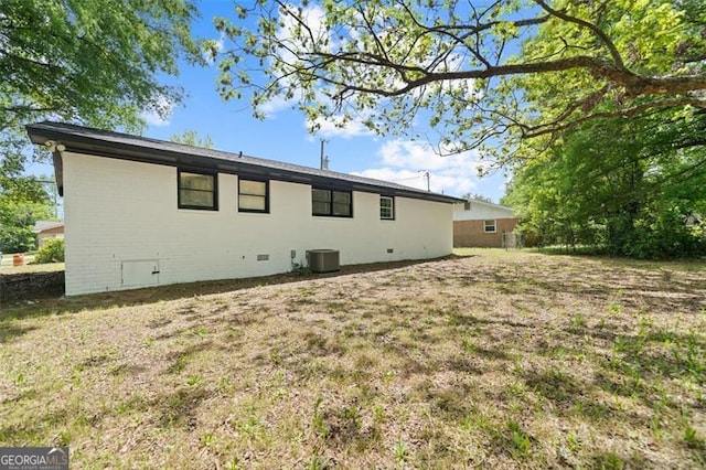rear view of property with central air condition unit, crawl space, and a yard