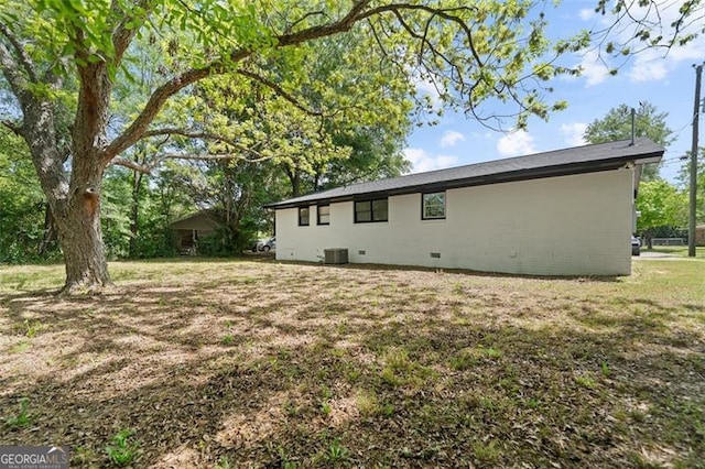 rear view of property with central air condition unit and a yard