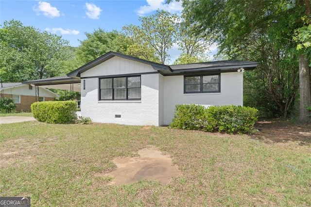 exterior space featuring a lawn, brick siding, and an attached carport
