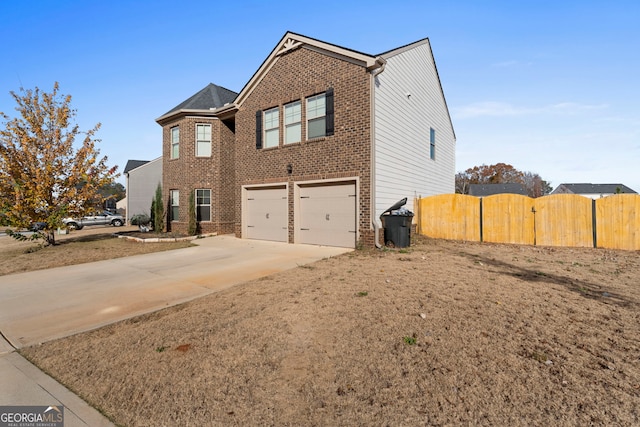 view of home's exterior with an attached garage, driveway, fence, and brick siding