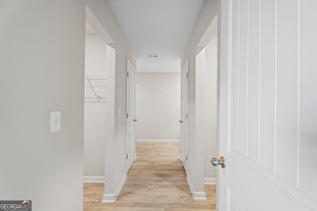 corridor featuring light wood-style floors, visible vents, and baseboards