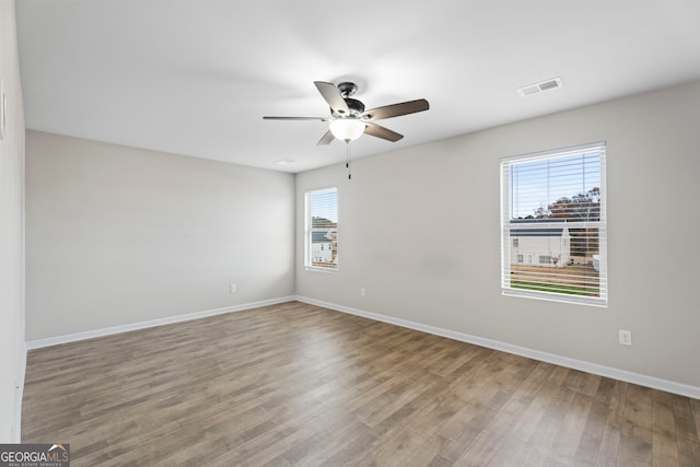 spare room with ceiling fan, baseboards, wood finished floors, and visible vents