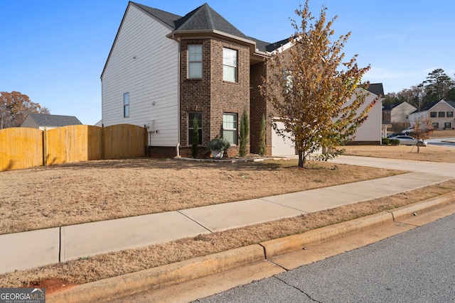 view of front facade with a gate, concrete driveway, fence, a garage, and brick siding