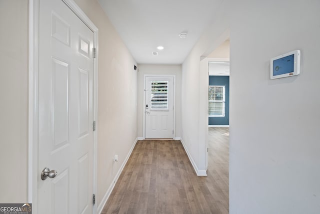hallway featuring baseboards, wood finished floors, and recessed lighting