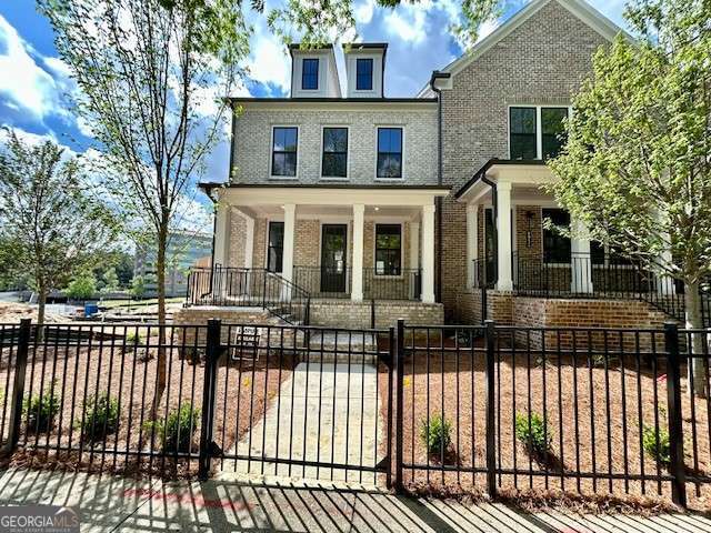 view of front of property with a fenced front yard, brick siding, and covered porch