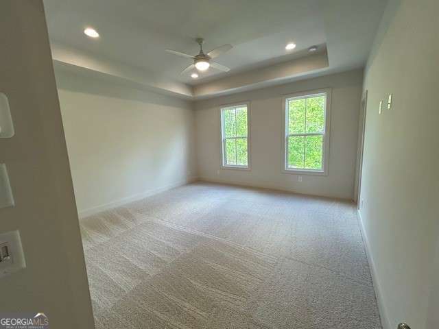 unfurnished room featuring recessed lighting, a raised ceiling, light carpet, baseboards, and ceiling fan
