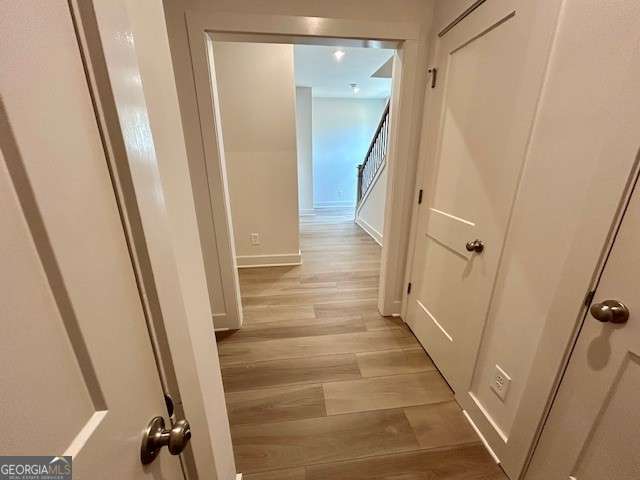 hall with baseboards and light wood-style floors