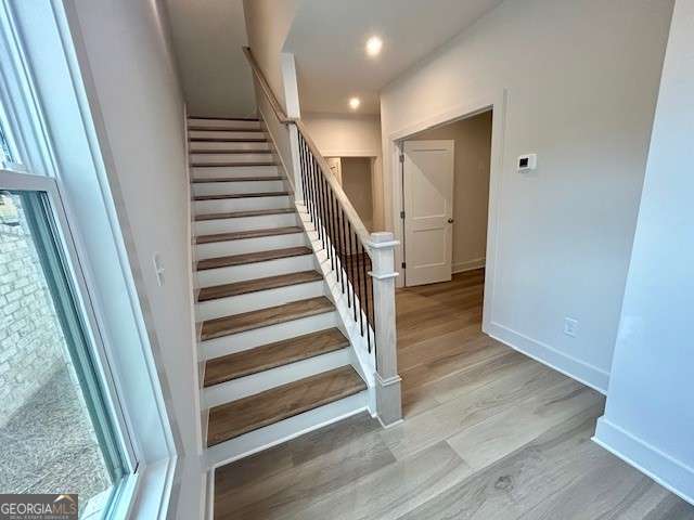 staircase with recessed lighting, wood finished floors, and baseboards