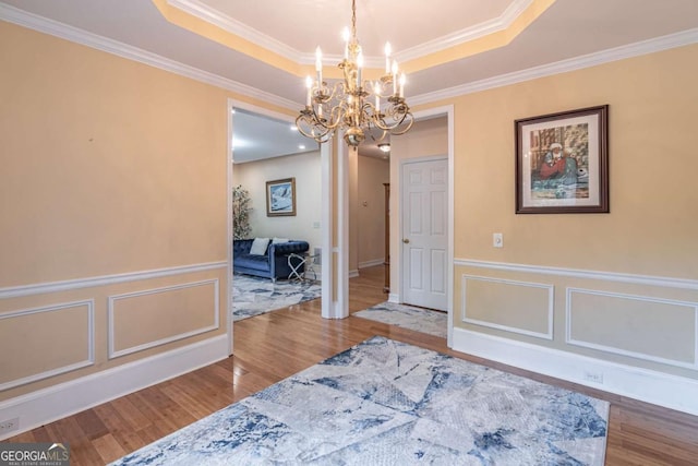 4319 Silver Peak Pkwy, Suwanee, GA 30024 - dining room featuring a raised ceiling, wood finished floors, a decorative wall, crown molding, and a notable chandelier