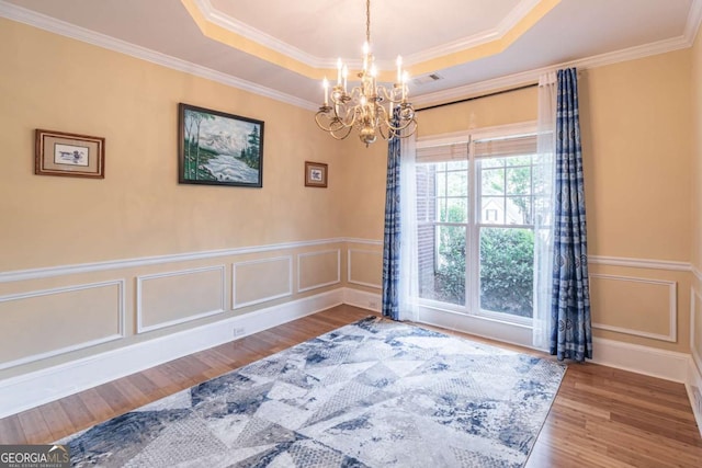 4319 Silver Peak Pkwy, Suwanee, GA 30024 - empty room with a raised ceiling, wood finished floors, ornamental molding, and a notable chandelier
