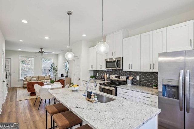 1095 Tucker Ave Unit 207, Atlanta, GA 30310 - kitchen with appliances with stainless steel finishes, a sink, backsplash, light wood-style floors, and white cabinets