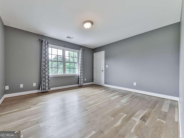 spare room featuring baseboards, visible vents, and light wood-type flooring