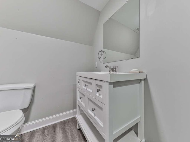 bathroom featuring baseboards, wood finished floors, toilet, and vanity