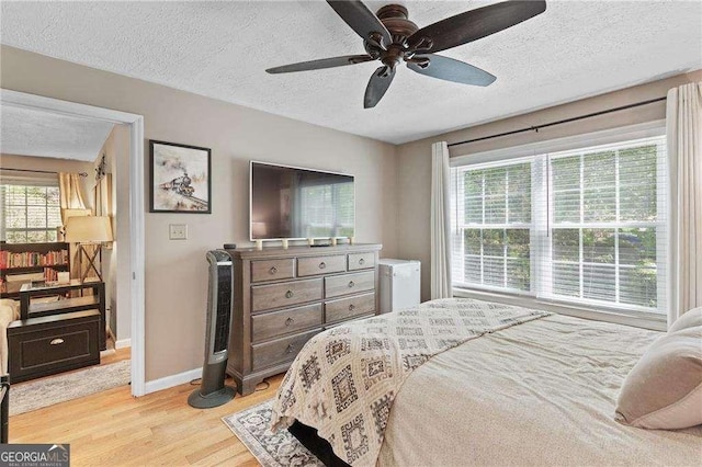 5566 River Heights Xing SE, Marietta, GA 30067 - bedroom featuring baseboards, a textured ceiling, light wood-style floors, and multiple windows