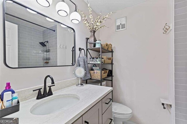 5566 River Heights Xing SE, Marietta, GA 30067 - full bathroom featuring a tile shower, visible vents, toilet, and vanity