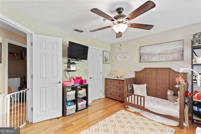 5566 River Heights Xing SE, Marietta, GA 30067 - bedroom with washer / dryer, wood finished floors, visible vents, and a textured ceiling