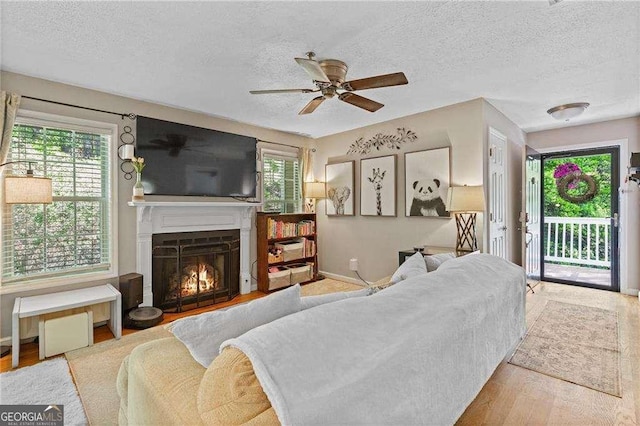 5566 River Heights Xing SE, Marietta, GA 30067 - living room featuring a textured ceiling, baseboards, wood finished floors, ceiling fan, and a lit fireplace