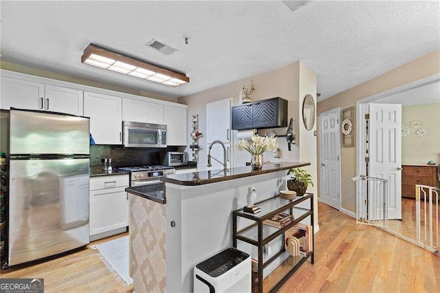 5566 River Heights Xing SE, Marietta, GA 30067 - kitchen with dark countertops, appliances with stainless steel finishes, white cabinetry, and a breakfast bar area