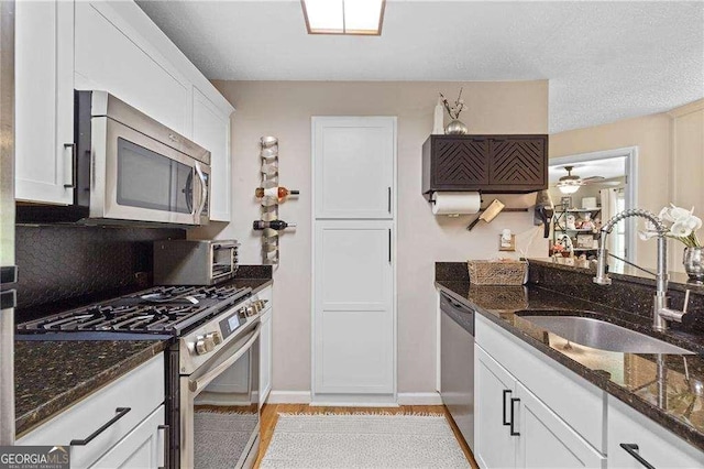 5566 River Heights Xing SE, Marietta, GA 30067 - kitchen featuring dark stone countertops, a sink, a toaster, stainless steel appliances, and white cabinets