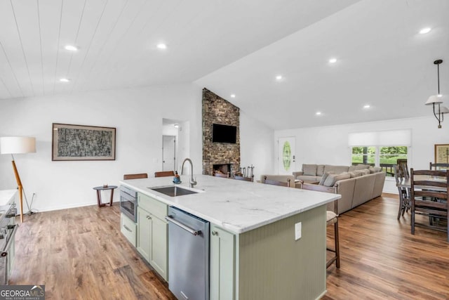 2180 Pine Lake Rd, Hiawassee, GA 30546 - kitchen featuring stainless steel appliances, a stone fireplace, wood finished floors, a sink, and a kitchen island with sink
