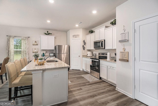 231 Limestone Cir, Conyers, GA 30013 - kitchen with stainless steel appliances, a breakfast bar, a sink, and white cabinetry