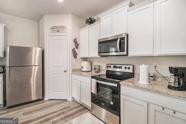 231 Limestone Cir, Conyers, GA 30013 - kitchen with stainless steel appliances, light wood finished floors, white cabinetry, light stone countertops, and recessed lighting