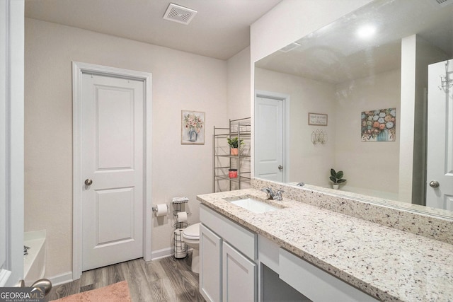 231 Limestone Cir, Conyers, GA 30013 - full bath featuring wood finished floors, vanity, baseboards, toilet, and visible vents