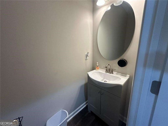 half bath with baseboards and vanity