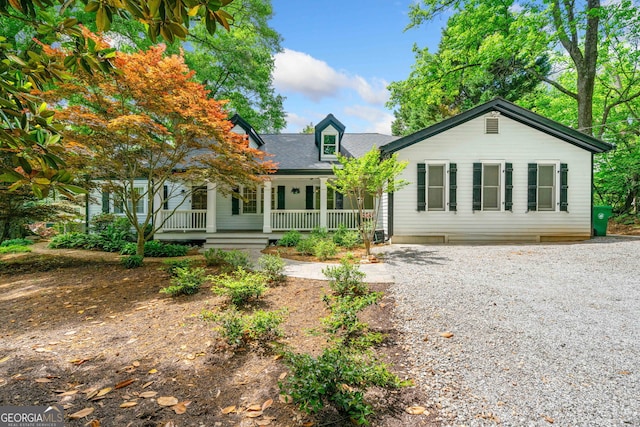 back of house featuring covered porch and gravel driveway