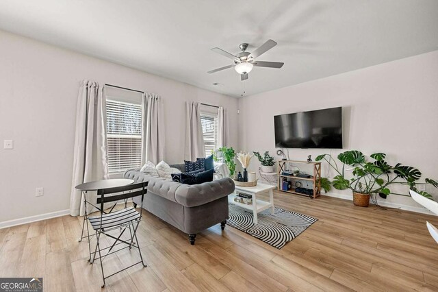 living room featuring baseboards, a ceiling fan, and light wood-type flooring