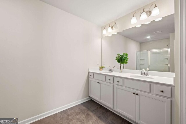 full bath featuring baseboards, a sink, a shower with shower door, and double vanity
