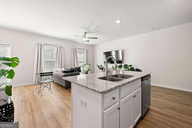 kitchen featuring a sink, open floor plan, light wood-style floors, a ceiling fan, and dishwasher