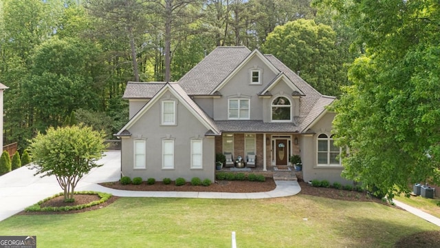 craftsman house with a porch, roof with shingles, a front yard, and stucco siding